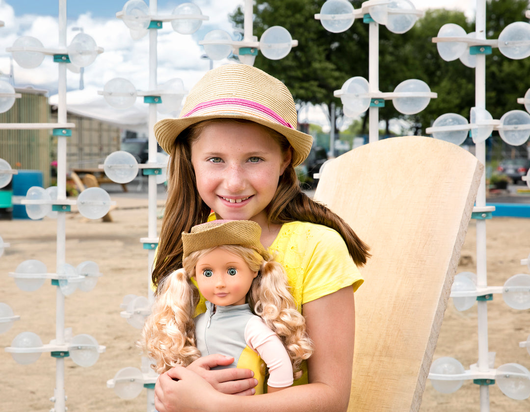 Little girl hugging doll on the beach